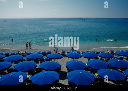 Des rangées de parasols bleus et des chaises longues sur la plage et la mer Méditerranée bleue idyllique à Monterosso Liguria Cinque Terre Italie Banque D'Images