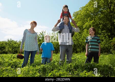 Parents et enfants (5-9) en portrait de champ de fraise Banque D'Images