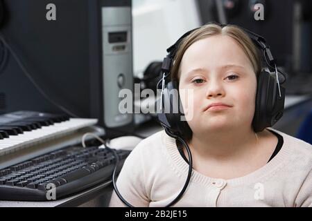 Portrait de fille (10-12) avec syndrome De Down portant des écouteurs dans le studio d'enregistrement à la maison Banque D'Images