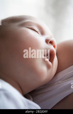 Bébé (1-6 mois) dormant dans les bras de la mère près Banque D'Images