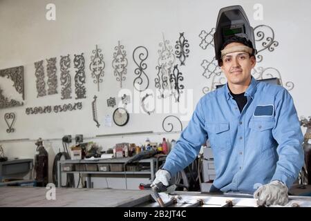 Portrait d'un jeune homme portant un équipement de protection dans un atelier métallique Banque D'Images