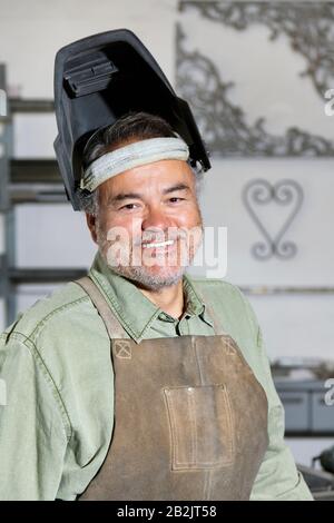 Portrait d'un homme mûr heureux portant un masque de soudage en atelier Banque D'Images