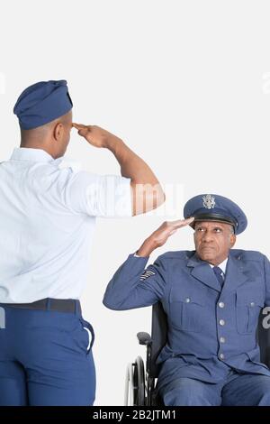 Le cadet masculin salue le bureau de la force aérienne senior en fauteuil roulant sur fond gris clair Banque D'Images