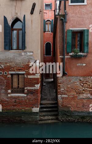 Bâtiments rouges pittoresques de Venise avec fenêtres vertes près du canal Banque D'Images