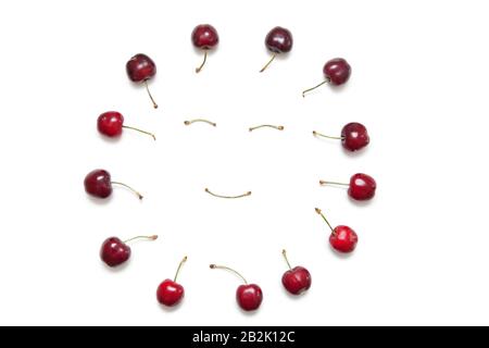 Cerises entourant le visage smiley fait par les tiges sur fond blanc Banque D'Images