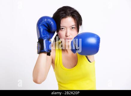 Portrait de la jeune femme asiatique portant des gants de boxe bleus sur fond blanc Banque D'Images