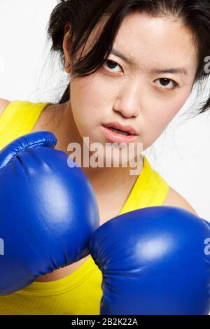 Portrait d'une femme asiatique sérieuse portant des gants de boxe sur fond blanc Banque D'Images