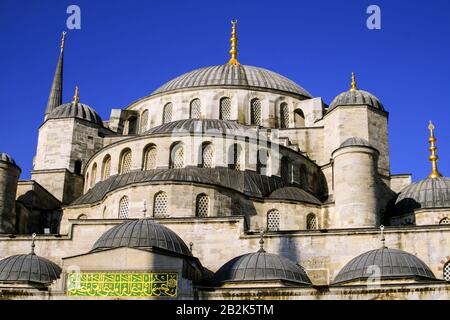 Une grande mosquée de pierre avec un grand dôme central flanqué de dômes plus petits et un grand minaret, le tout surmonté de parquets dorés. La structure comprend des fenêtres cintrées avec un treillis complexe et un Banque D'Images