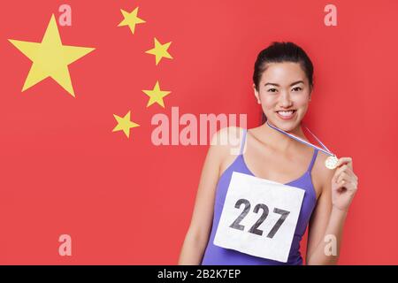 Portrait de jeune médaillée souriante debout contre le drapeau chinois Banque D'Images