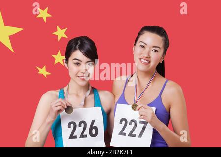 Portrait de jeunes médaillés souriants se tenant contre le drapeau chinois Banque D'Images