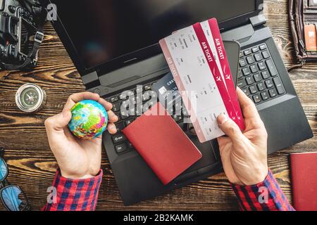 Préparez-vous à un voyage passionnant. Man livre des vols en tapant sur un ordinateur portable et en payant avec une carte de crédit sur un fond en bois. La vue du haut Banque D'Images