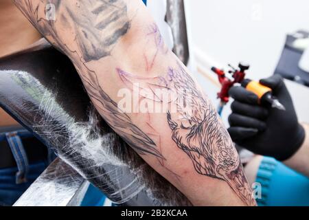 Image rognée du bras de l'homme tatouant l'artiste en studio Banque D'Images