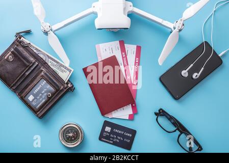 Les choses nécessaires pour le vol en vacances. Billets d'avion, passeport, carte berceaux, argent, téléphone, quadricoptère drone, caméra sur fond bleu. Conceps Banque D'Images