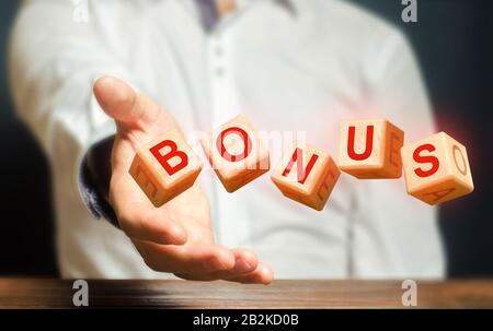 Les cubes lancés par un homme font le BONUS de mot. Recevez des bonus, des récompenses et des préférences. Augmentation de salaire, prime de salaire pour les vacances.Achat Favorable et spe Banque D'Images