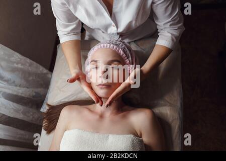 Salle de cosmologie, esthéticienne fait un massage facial à une jeune belle fille. Belle peau saine Banque D'Images