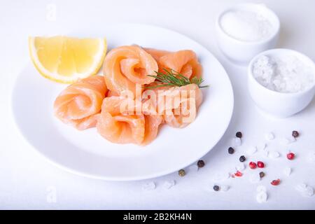 Saumon salé sur une plaque blanche avec citron et aneth. Fond blanc, mise au point sélective, gros plan. Banque D'Images