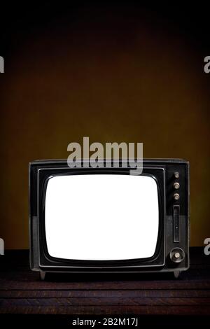 Ancienne télévision portable, avec écran vide. Table en bois et fond marron. Version verticale. Concept d'obsolescence, de modernisation ou de technologie Banque D'Images