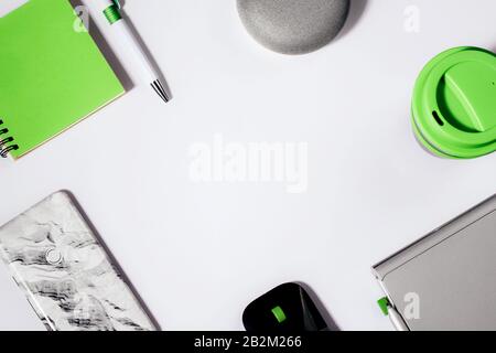 Concept d'assistant numérique. Enceinte plate avec éclairage LED activée avec smartphone court, bloc-notes vert, stylo et tasse à café réutilisable. Banque D'Images