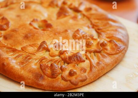 Tarte russe aux pommes de terre et aux champignons sur la table. Grand gâteau fraîchement cuit décoré avec des fleurs de leur pâte, tarte russe traditionnelle Banque D'Images