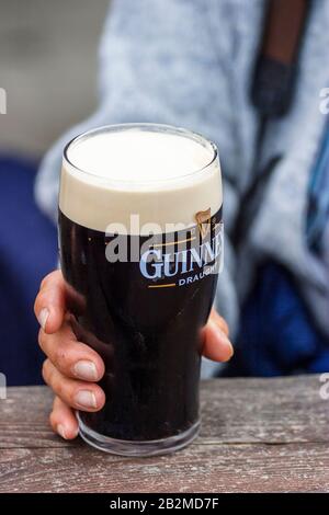 Femme tenant une pinte de guinness dans un restaurant extérieur Banque D'Images