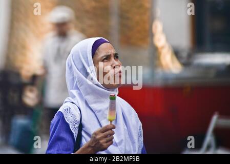 Femme musulmane portant du hijab et mangeant une rame de glace. Souq Waqif, Doha, Qatar Banque D'Images