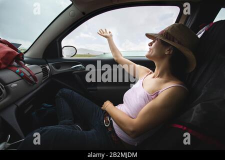 Fille mettant la main à travers les fenêtres de voiture pour sentir la pluie. Voyage avec concept de voiture. Banque D'Images