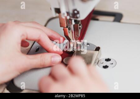 Un artisan en cuir produit des articles en cuir sur une machine à coudre dans sa boutique. Travail à la main. Gros plan. Banque D'Images