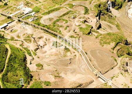Une photographie aérienne montre une grande exploitation de carrière avec de la terre excavée, des tas de roches et de gravier, et de multiples routes d'accès. Une route pavée à deux voies traverse le site, traversant une petite Banque D'Images