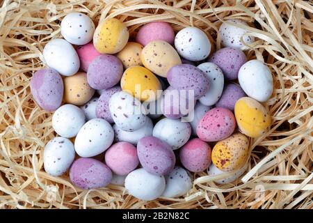 Un indice des œufs de bonbons de Pâques sur fond de paille Banque D'Images