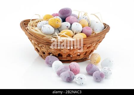 Bonbons de Pâques dans un panier isolé sur fond blanc Banque D'Images