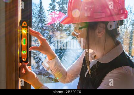 gros plan sur la femme inspecteur de construction utilisant le niveau d'esprit torpille pour mesurer une surface intérieure verticale à côté d'une fenêtre. inspection de la qualité de l'air Banque D'Images