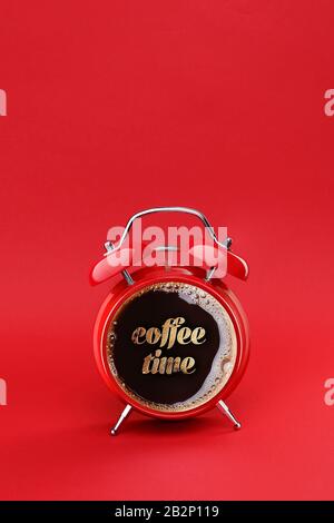 Café du matin. Concept de temps de café. Pause café. Double réveil rouge vintage avec tasse de café et texte crème isolé sur fond rouge Banque D'Images