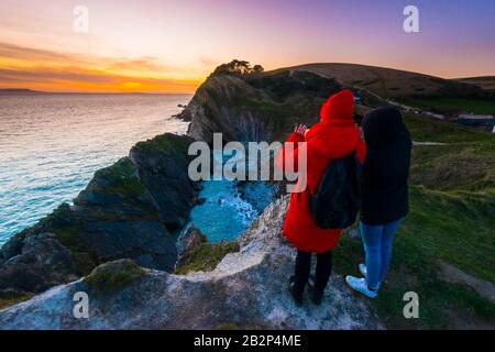 Stair Hole, Lullworth, Dorset, Royaume-Uni. 3 mars 2020. Météo britannique. Deux femmes prennent la vue sur le coucher du soleil alors qu'elles se tiennent sur la falaise au-dessus de Stair Hole à Lullworth à Dorset à la fin d'une journée ensoleillée froide. Crédit Photo : Graham Hunt/Alay Live News Banque D'Images