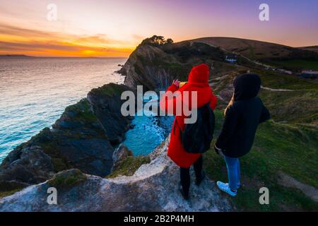 Stair Hole, Lullworth, Dorset, Royaume-Uni. 3 mars 2020. Météo britannique. Deux femmes prennent la vue sur le coucher du soleil alors qu'elles se tiennent sur la falaise au-dessus de Stair Hole à Lullworth à Dorset à la fin d'une journée ensoleillée froide. Crédit Photo : Graham Hunt/Alay Live News Banque D'Images