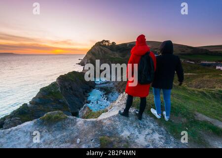 Stair Hole, Lullworth, Dorset, Royaume-Uni. 3 mars 2020. Météo britannique. Deux femmes prennent la vue sur le coucher du soleil alors qu'elles se tiennent sur la falaise au-dessus de Stair Hole à Lullworth à Dorset à la fin d'une journée ensoleillée froide. Crédit Photo : Graham Hunt/Alay Live News Banque D'Images