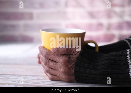 Une femme âgée tenant une tasse de café ou de thé dans les mains Banque D'Images