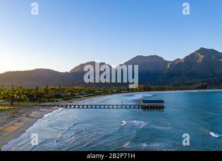 Image panoramique aérienne au lever du soleil au large de la côte au-dessus de la baie Hanalei et de la jetée sur l'île hawaïenne de Kauai Banque D'Images