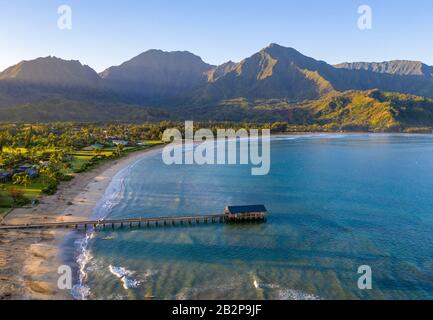 Image panoramique aérienne au lever du soleil au large de la côte au-dessus de la baie Hanalei et de la jetée sur l'île hawaïenne de Kauai Banque D'Images