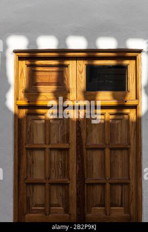 L'ombre d'une balustrade tombe à travers une fenêtre en bois avec volets dans un détail architectural abstrait, Guia de Isora, Tenerife, îles Canaries, Espagne Banque D'Images
