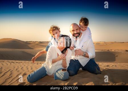 Portrait de groupe familial, se divertir ensemble, dans un désert avec des dunes de sable en arrière-plan, Dubaï, Banque D'Images