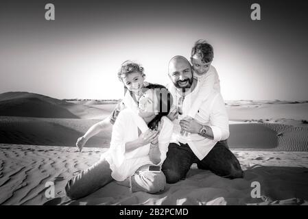 Portrait de groupe familial, se divertir ensemble, dans un désert avec des dunes de sable en arrière-plan, Dubaï, Banque D'Images