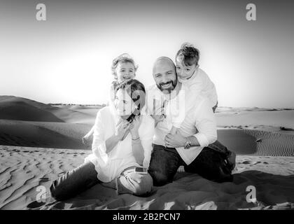 Portrait de groupe familial, se divertir ensemble, dans un désert avec des dunes de sable en arrière-plan, Dubaï, Banque D'Images