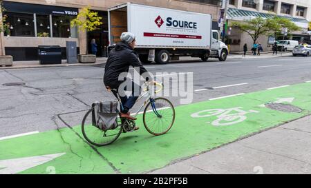 Homme à vélo dans la voie verte peinte de vélo dans le centre-ville de Toronto. Banque D'Images