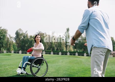 une jeune femme handicapée jetant un disque volant à un petit ami dans le parc Banque D'Images