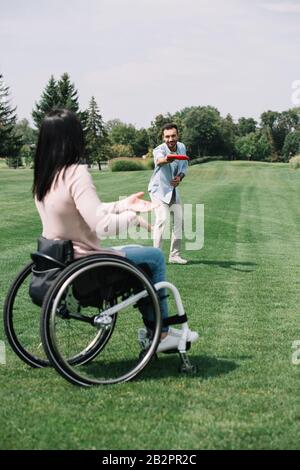 un jeune homme gai qui jeta un disque volant à une petite amie pour handicapés dans le parc Banque D'Images