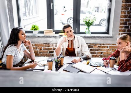 trois amis multiethniques assis à la table et étudiant en appartement Banque D'Images