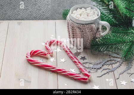 Tasse de guimauves et de cannes de bonbons entourée de décorations de Noël sur une table en bois Banque D'Images