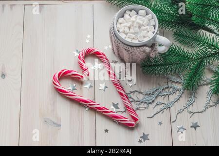 Tasse de guimauves et de cannes de bonbons entourée de décorations de Noël sur une table en bois Banque D'Images