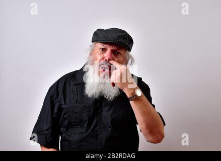 Homme avec la barbe pointant vers son nez avec son doigt avec un visage surpris Banque D'Images