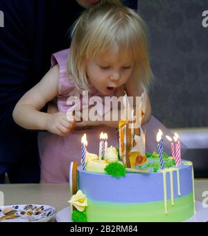 petite fille européenne soufflant des bougies sur un gâteau à son anniversaire Banque D'Images